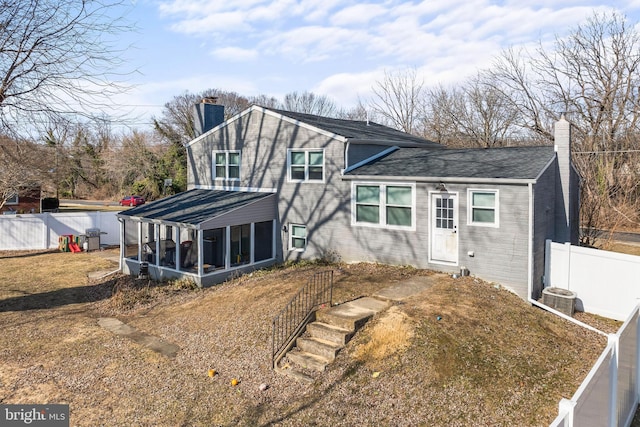 view of front of property featuring central air condition unit, brick siding, fence, a sunroom, and a chimney