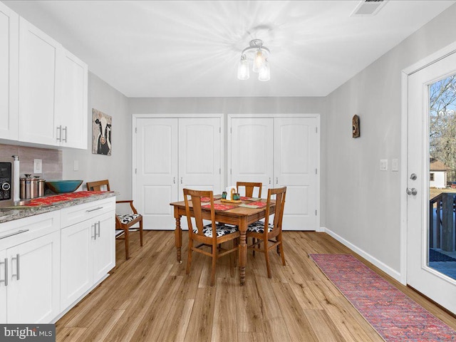 dining room with light wood-type flooring, baseboards, and visible vents