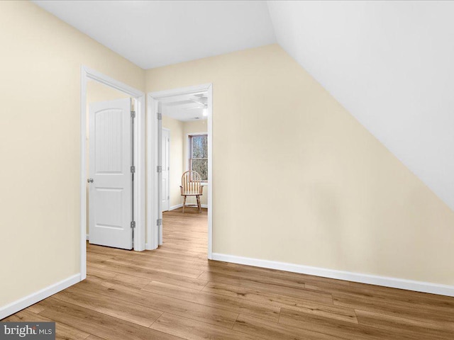 additional living space with vaulted ceiling, light wood-style flooring, and baseboards