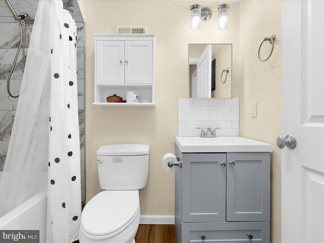 bathroom with toilet, vanity, baseboards, tasteful backsplash, and shower / bath combo