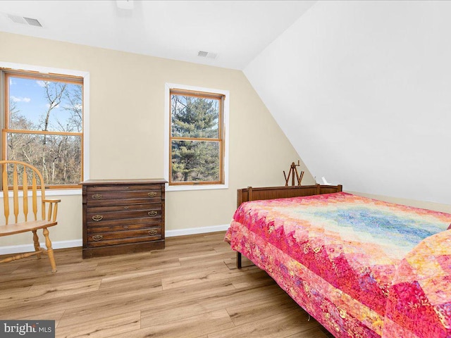 bedroom featuring lofted ceiling, wood finished floors, visible vents, and baseboards