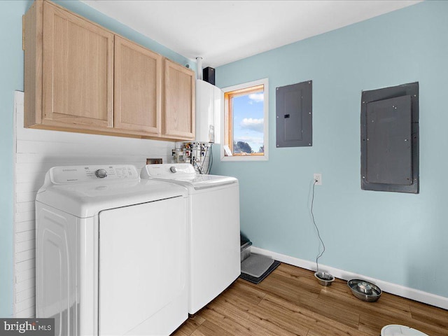 washroom featuring cabinet space, electric panel, light wood-style floors, and washer and dryer