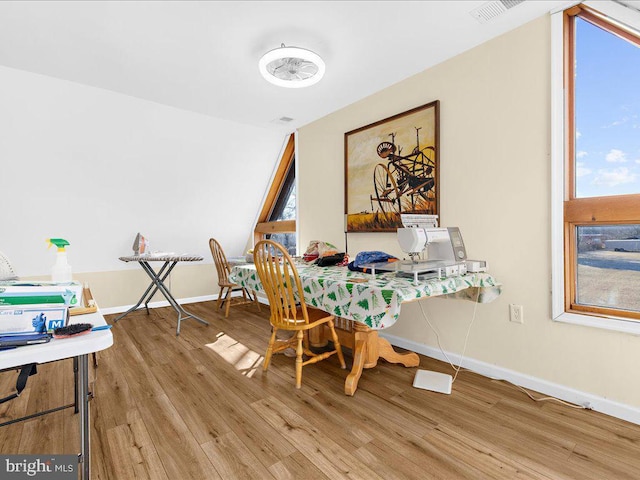 dining space featuring light wood-type flooring, visible vents, and baseboards