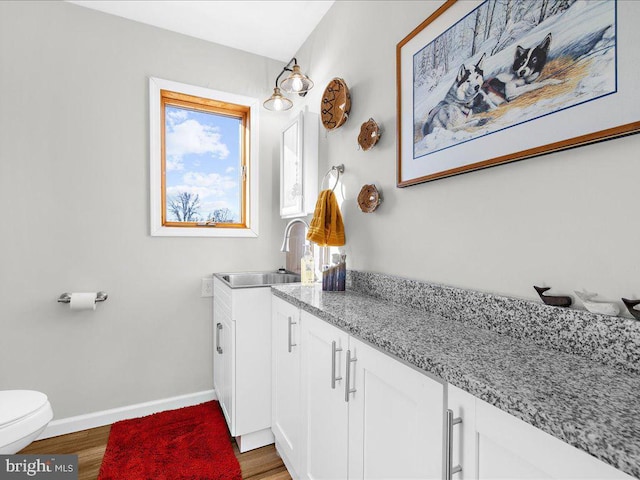 bathroom featuring toilet, baseboards, wood finished floors, and vanity