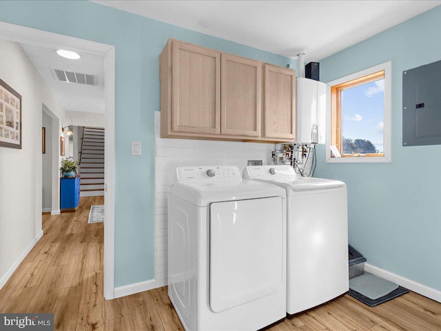 washroom featuring washer and clothes dryer, cabinet space, visible vents, light wood-style flooring, and electric panel