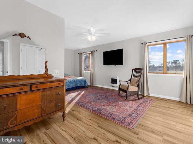 bedroom featuring light wood-type flooring, multiple windows, and heating unit