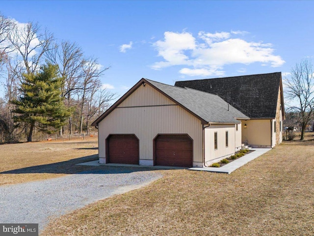 view of property exterior with driveway, a shingled roof, and a lawn