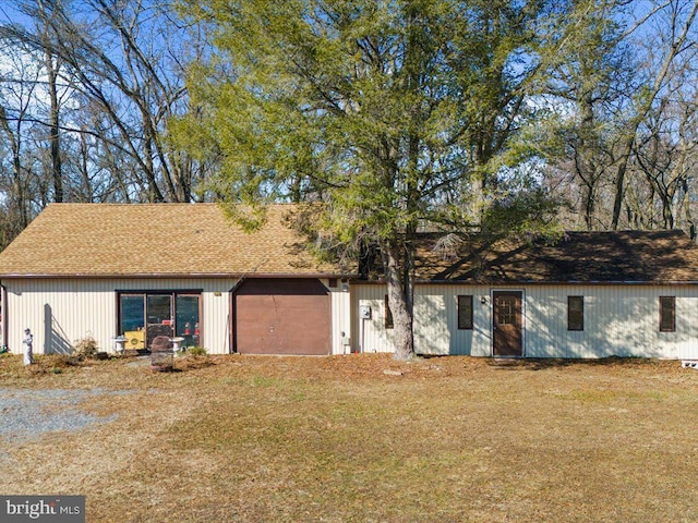 ranch-style home with roof with shingles and a front lawn