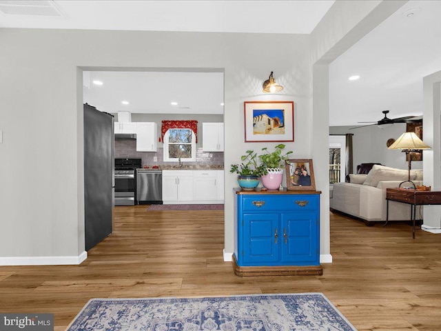 interior space featuring a ceiling fan, visible vents, light wood-style flooring, and baseboards