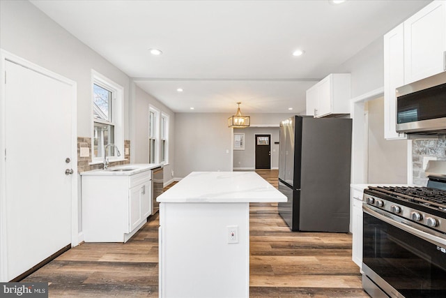 kitchen featuring wood finished floors, appliances with stainless steel finishes, a kitchen island, and white cabinets