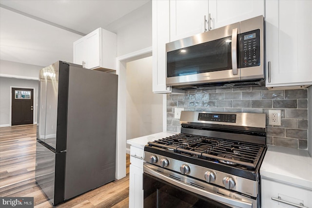 kitchen featuring white cabinets, light wood-style floors, light countertops, appliances with stainless steel finishes, and decorative backsplash