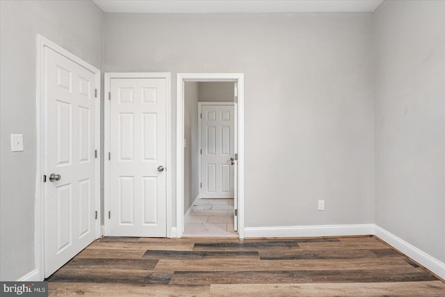 unfurnished bedroom with wood finished floors and baseboards