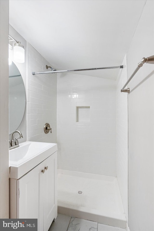 full bathroom featuring marble finish floor, a tile shower, and vanity