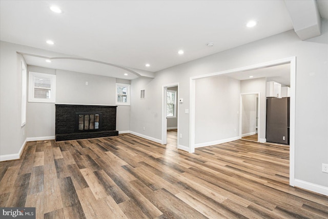 unfurnished living room with baseboards, wood finished floors, and recessed lighting