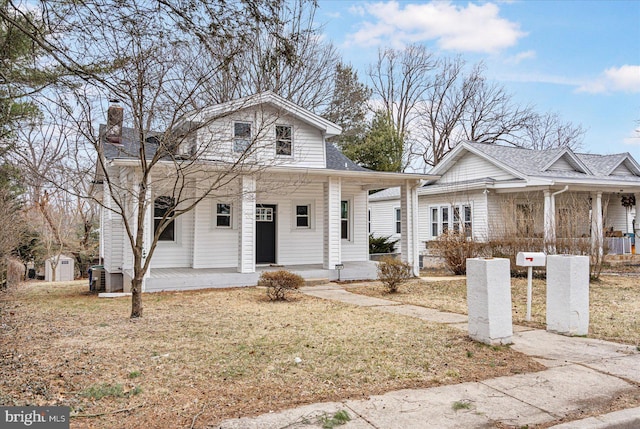 bungalow-style house featuring covered porch, central AC unit, and roof with shingles