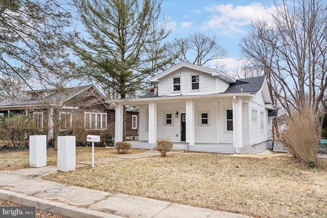 bungalow featuring a porch, a front lawn, and a shingled roof