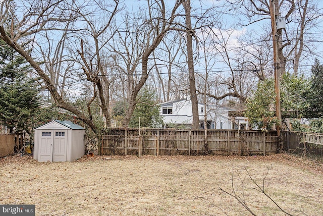 view of yard featuring an outbuilding, a fenced backyard, and a storage shed