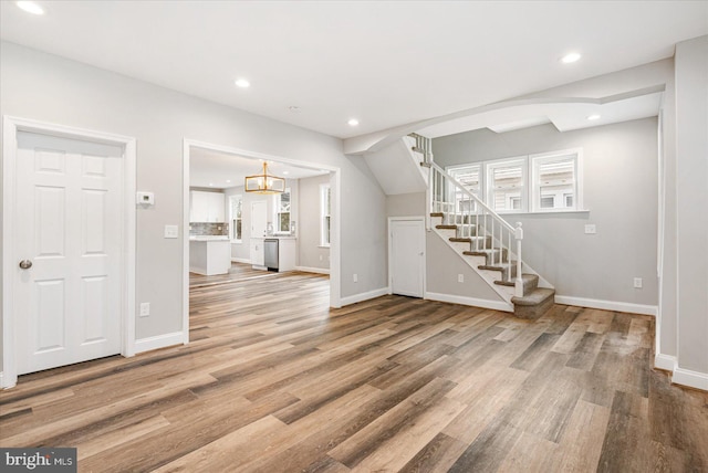 unfurnished living room featuring stairway, wood finished floors, and recessed lighting