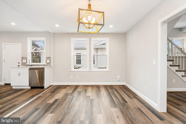 unfurnished dining area featuring recessed lighting, dark wood finished floors, stairway, and baseboards