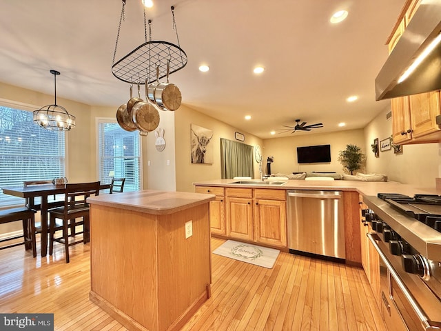 kitchen featuring a peninsula, stainless steel dishwasher, light wood-type flooring, under cabinet range hood, and a sink