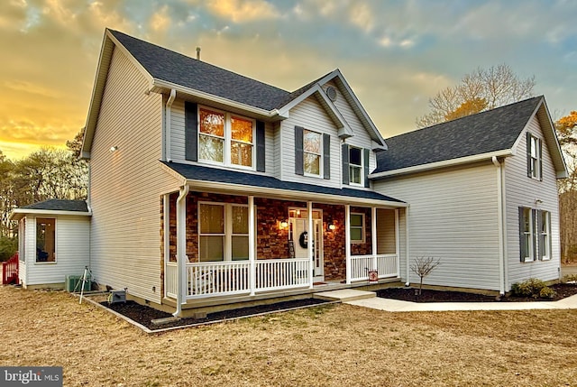 traditional home with covered porch and roof with shingles