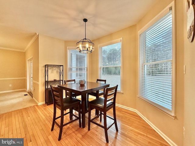 dining area featuring baseboards, ornamental molding, light wood-style flooring, and a notable chandelier