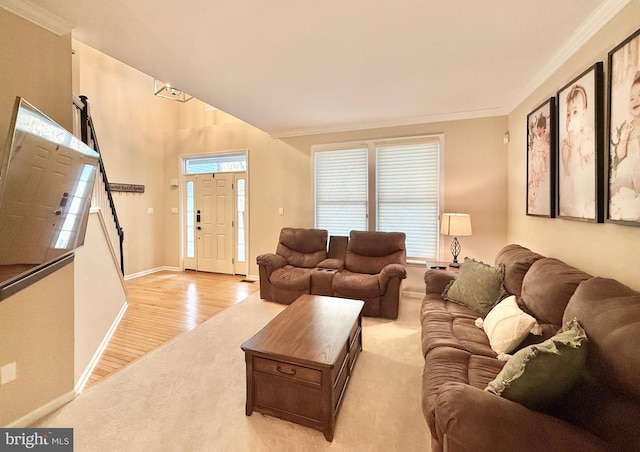 carpeted living room with ornamental molding, baseboards, and wood finished floors