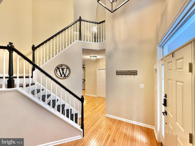 entrance foyer with stairs, a high ceiling, baseboards, and hardwood / wood-style floors