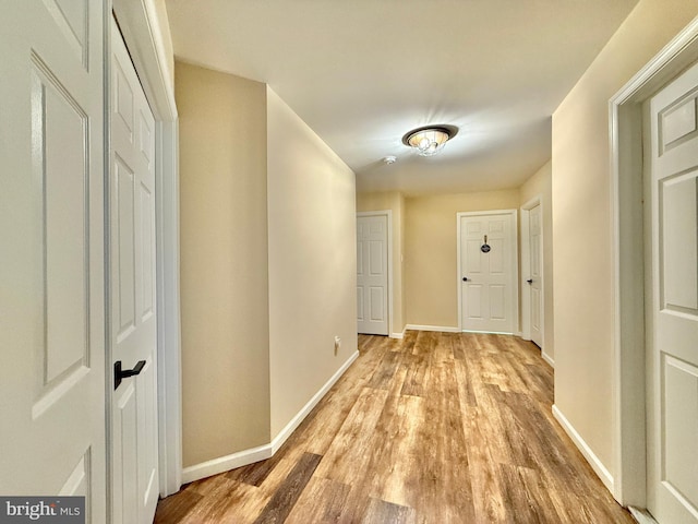 corridor with light wood-style flooring and baseboards