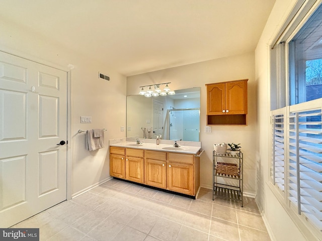 full bathroom with double vanity, baseboards, visible vents, a shower stall, and a sink