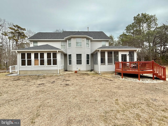 rear view of house with a sunroom, roof with shingles, and a wooden deck