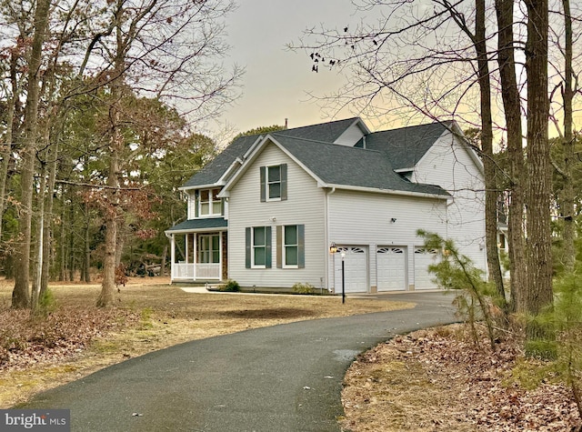 view of front facade featuring aphalt driveway, a porch, a shingled roof, and a garage