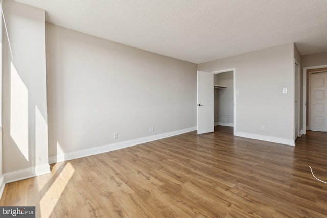 unfurnished bedroom featuring baseboards, a textured ceiling, and wood finished floors