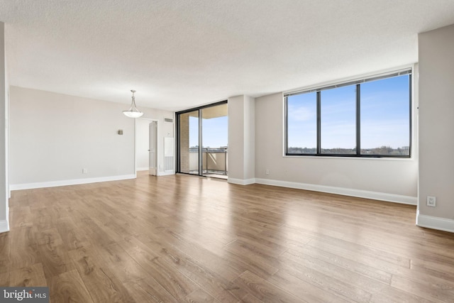 unfurnished living room with wood finished floors, baseboards, and a textured ceiling