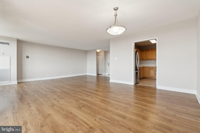 interior space with light wood finished floors, visible vents, and baseboards