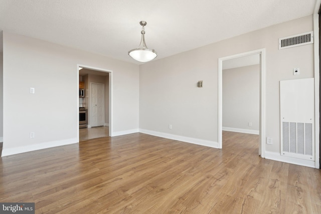 spare room with visible vents, baseboards, and light wood-style flooring