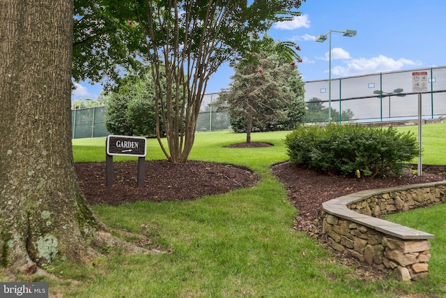 view of community featuring a lawn and fence