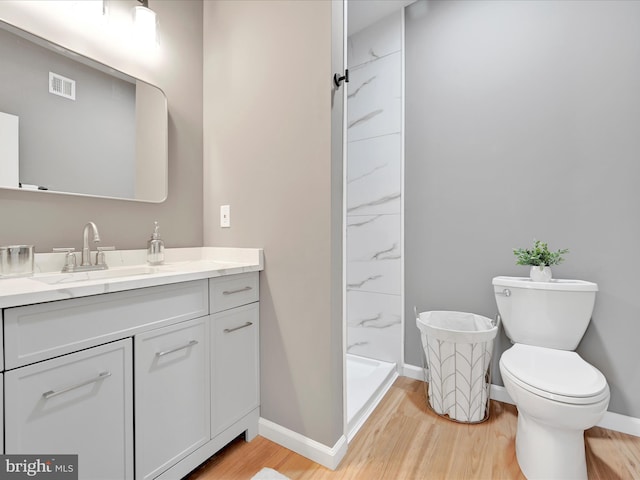 bathroom with visible vents, toilet, wood finished floors, vanity, and a shower stall