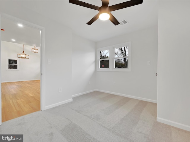 empty room with carpet flooring, ceiling fan, visible vents, and baseboards