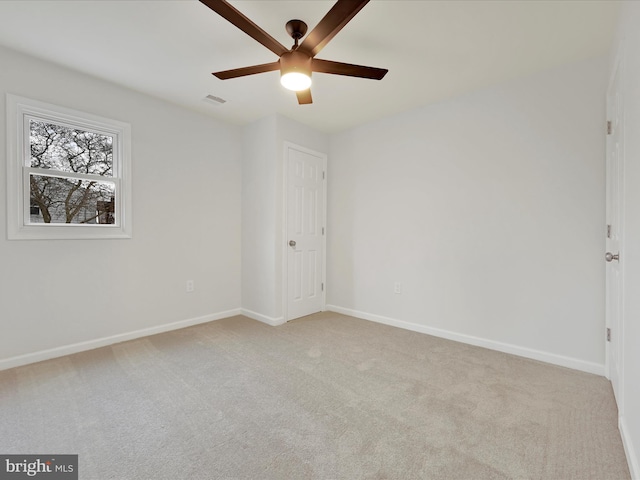 unfurnished room featuring light carpet, a ceiling fan, visible vents, and baseboards