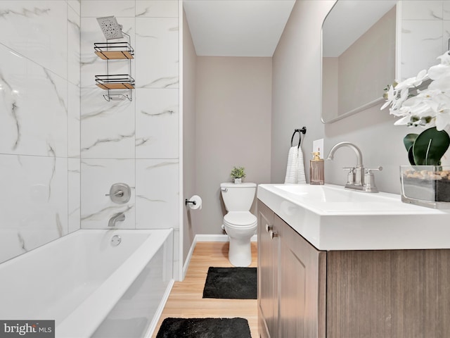 full bathroom featuring toilet, wood finished floors, vanity, baseboards, and washtub / shower combination