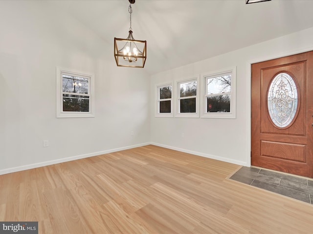 entryway featuring a notable chandelier, light wood finished floors, and baseboards