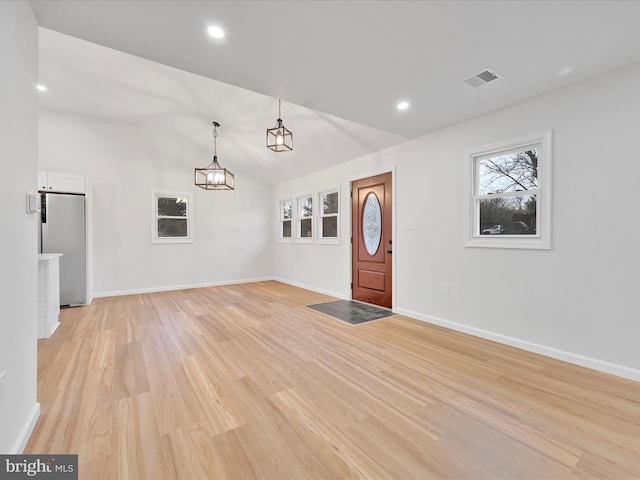 entrance foyer featuring lofted ceiling, baseboards, visible vents, and light wood-style floors