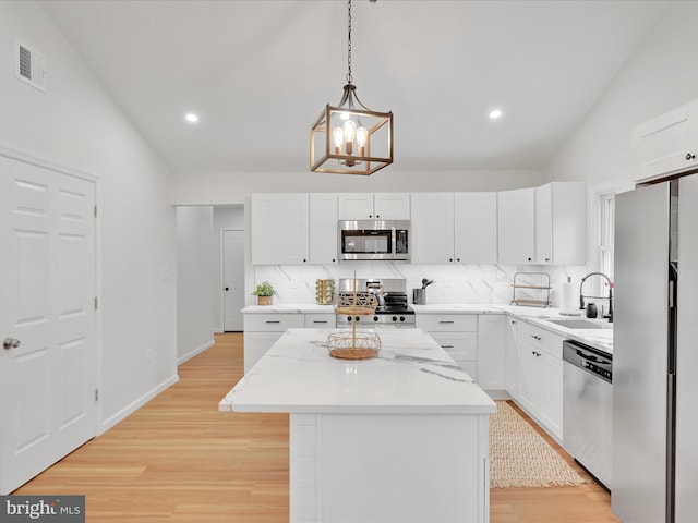 kitchen featuring tasteful backsplash, visible vents, stainless steel appliances, light wood-style floors, and a sink