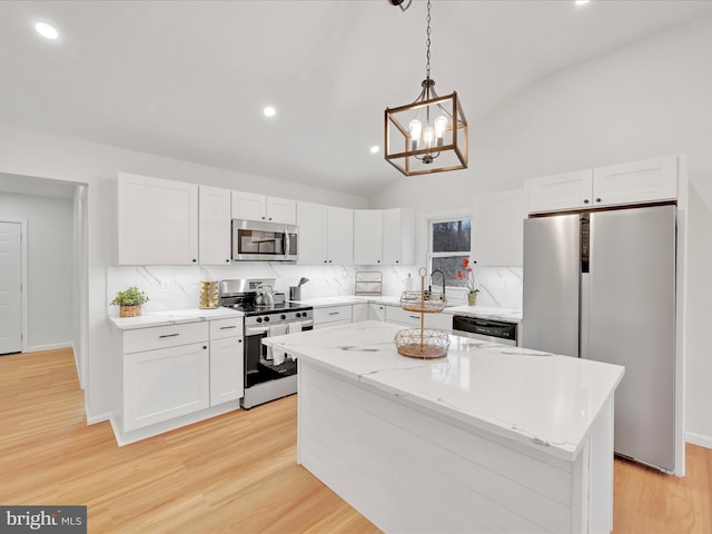 kitchen with vaulted ceiling, stainless steel appliances, light wood finished floors, and white cabinetry