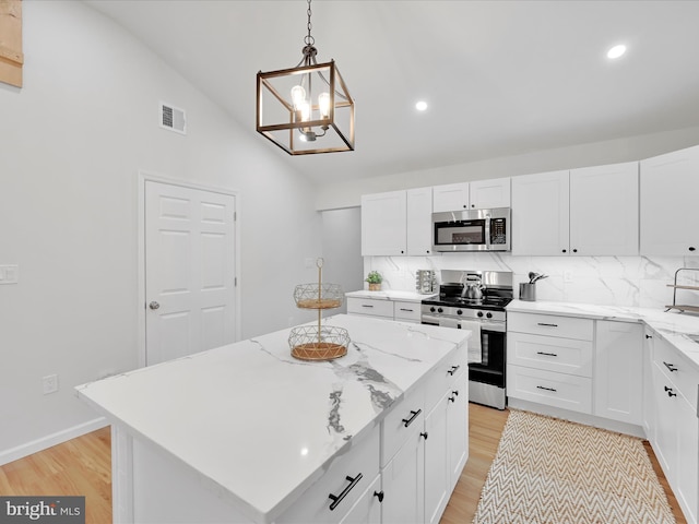 kitchen with stainless steel appliances, lofted ceiling, tasteful backsplash, visible vents, and light wood-style flooring