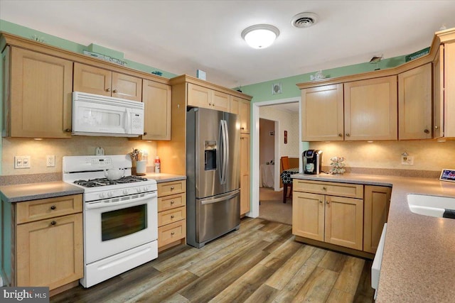 kitchen featuring white appliances, light wood-type flooring, light brown cabinets, and visible vents