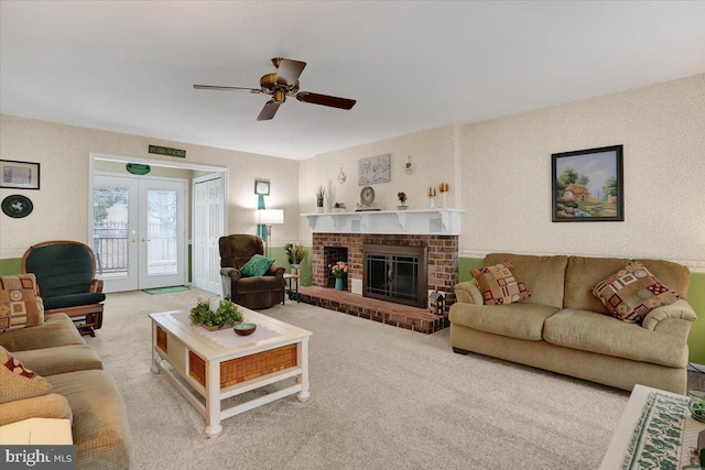 living room featuring a ceiling fan, french doors, carpet flooring, and a fireplace