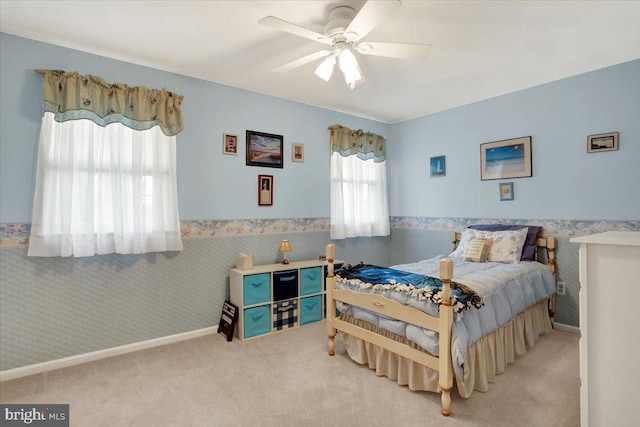 carpeted bedroom featuring a wainscoted wall, ceiling fan, and wallpapered walls