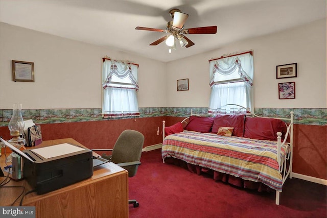 bedroom with ceiling fan, wainscoting, and carpet flooring